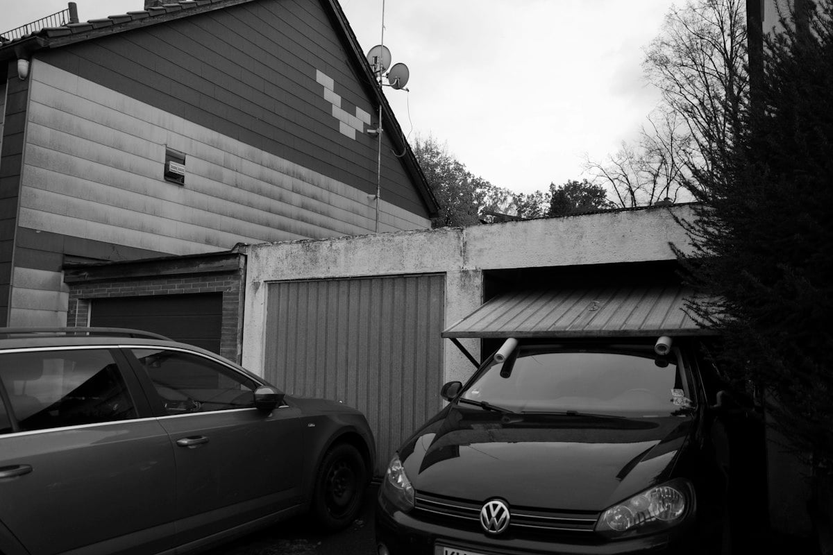 Two cars parked outside a garage with the door partly open